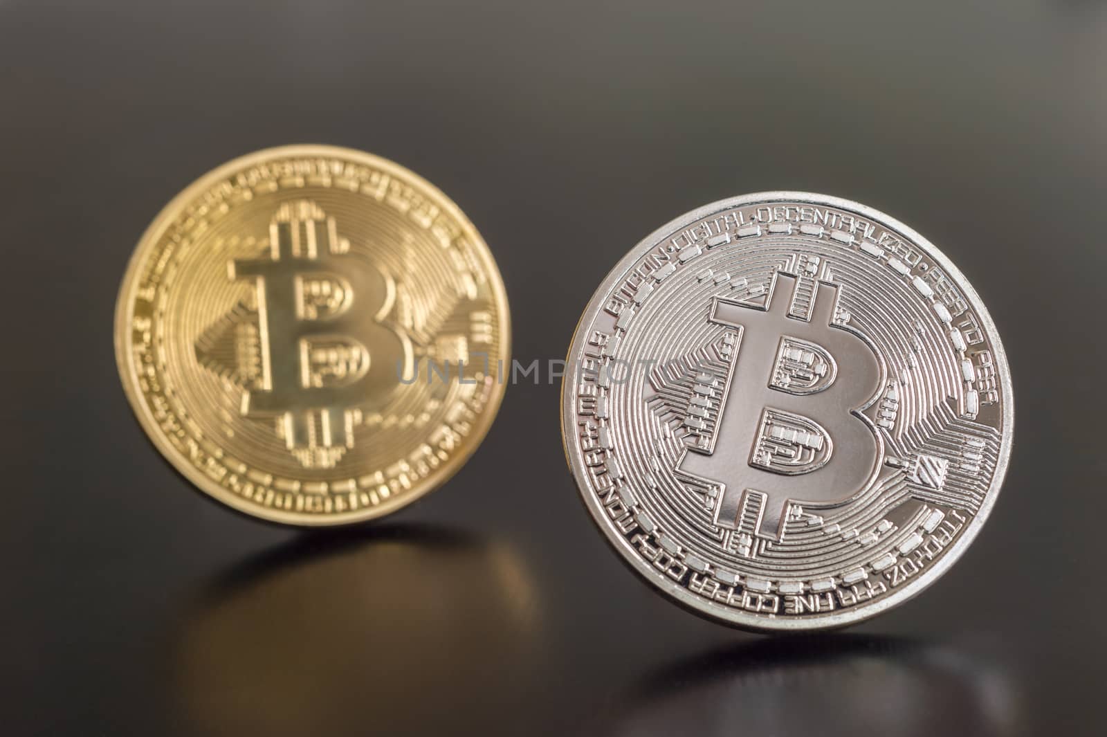 Two cryptocurrency Bitcoin metallic coins over grey background