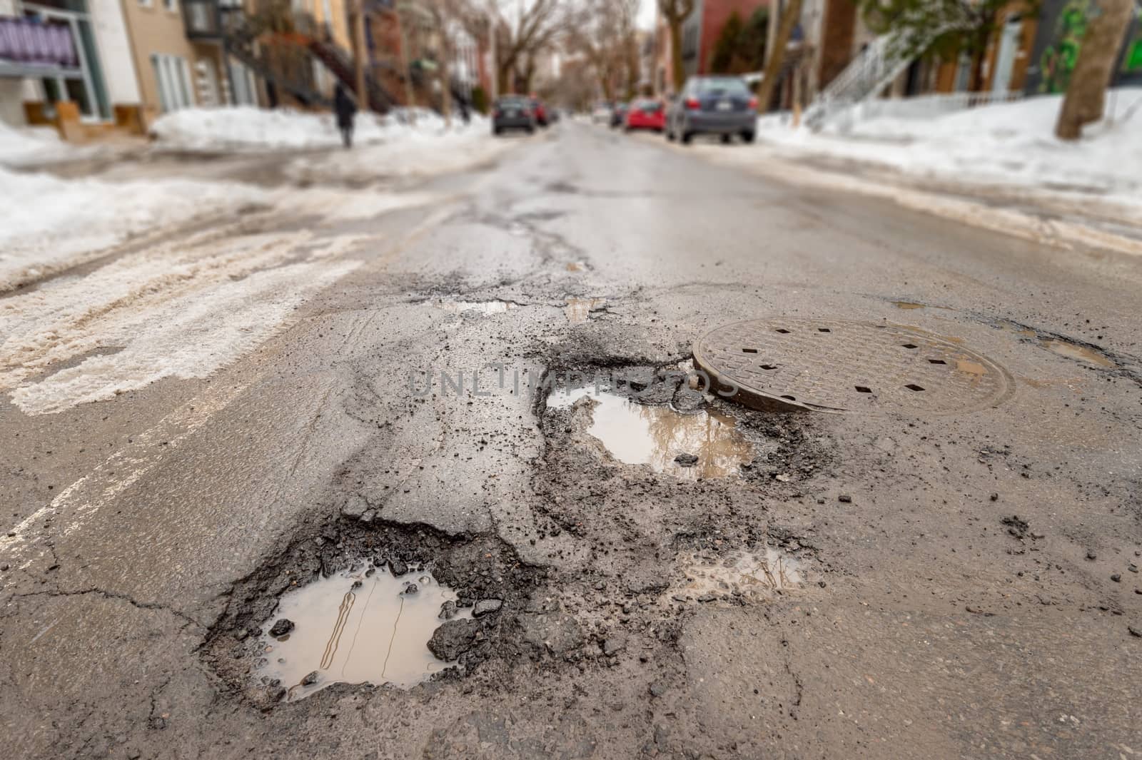 Large potholes in Montreal street, in Winter