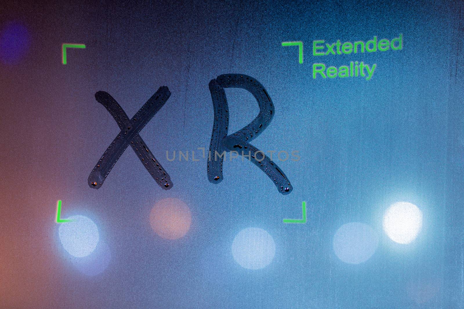 the word xr handwritten by finger on wet window glass with green overlay with words extended reality and corner frame by z1b