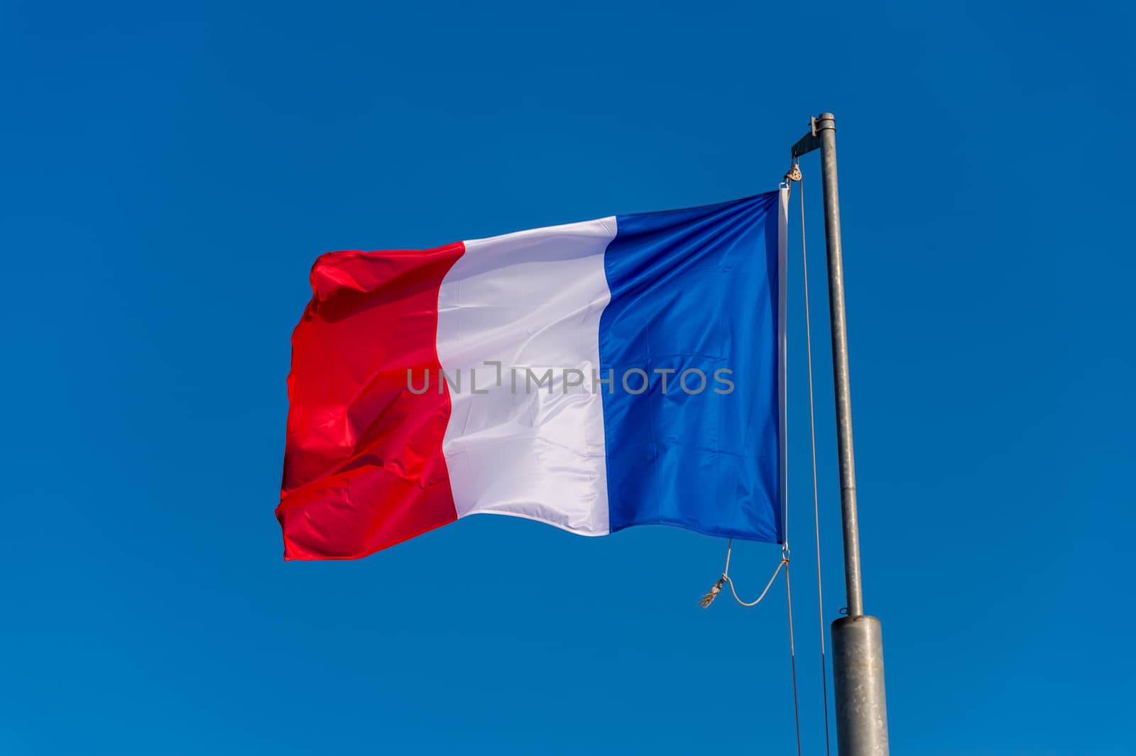 French flag waving against blue sky in Boulogne sur Mer, France.