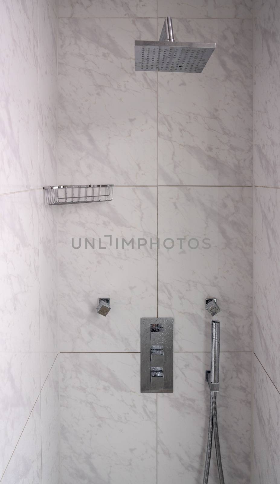 Modern tiled bathroom shower with rain head body sprays and hand attachment