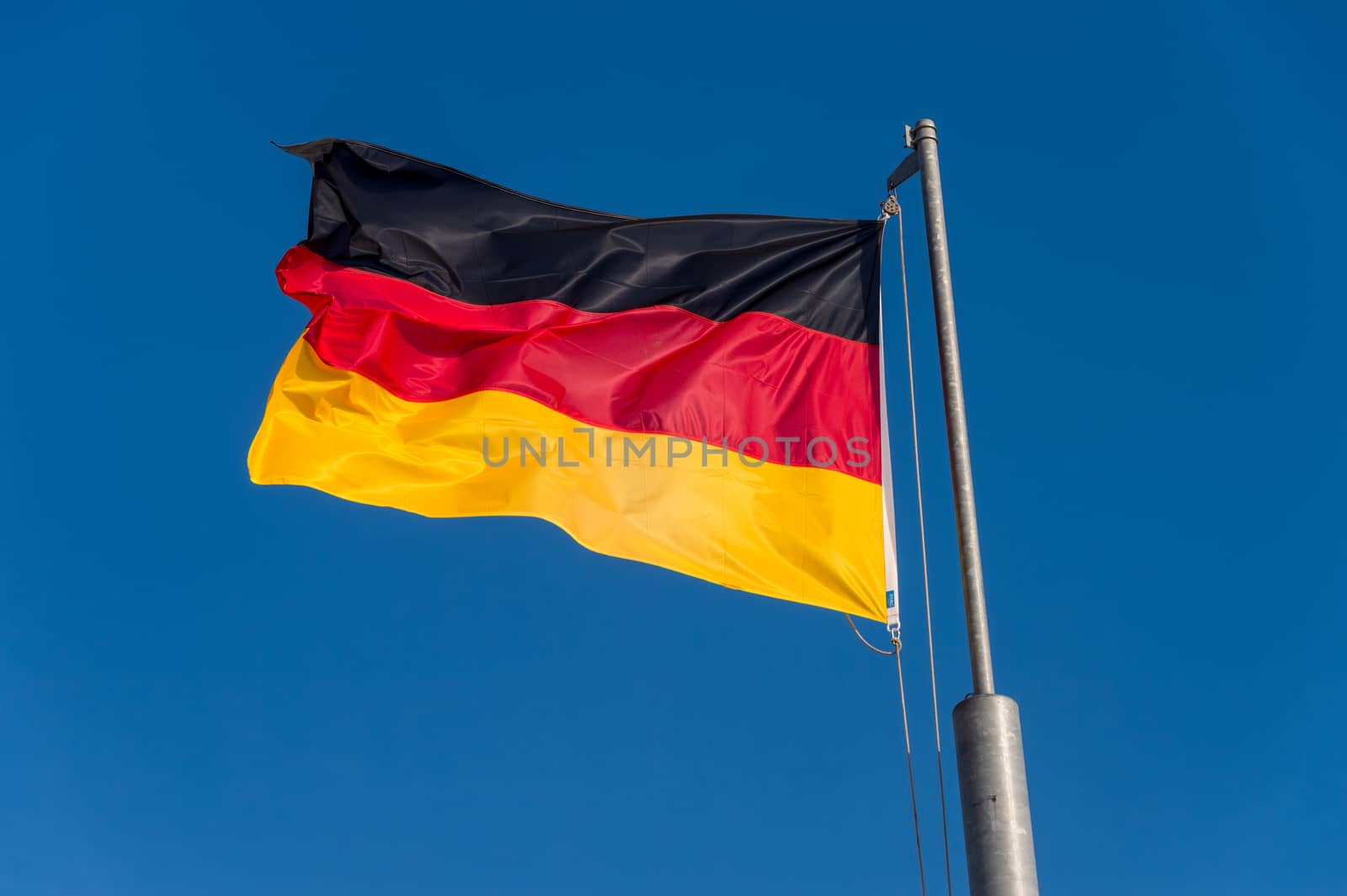 German flag waving against blue sky in Boulogne sur Mer, France. by mbruxelle