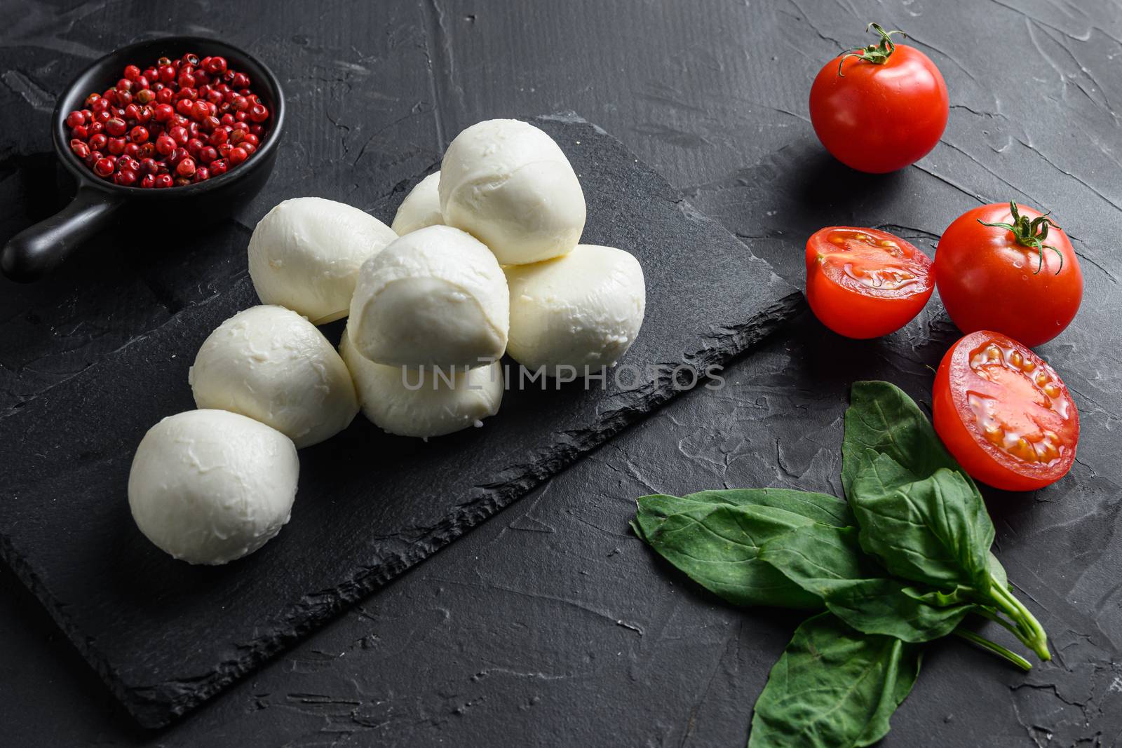 Mozzarella cheese, basil tomato cherry over old black backgroundon black stone slate by Ilianesolenyi