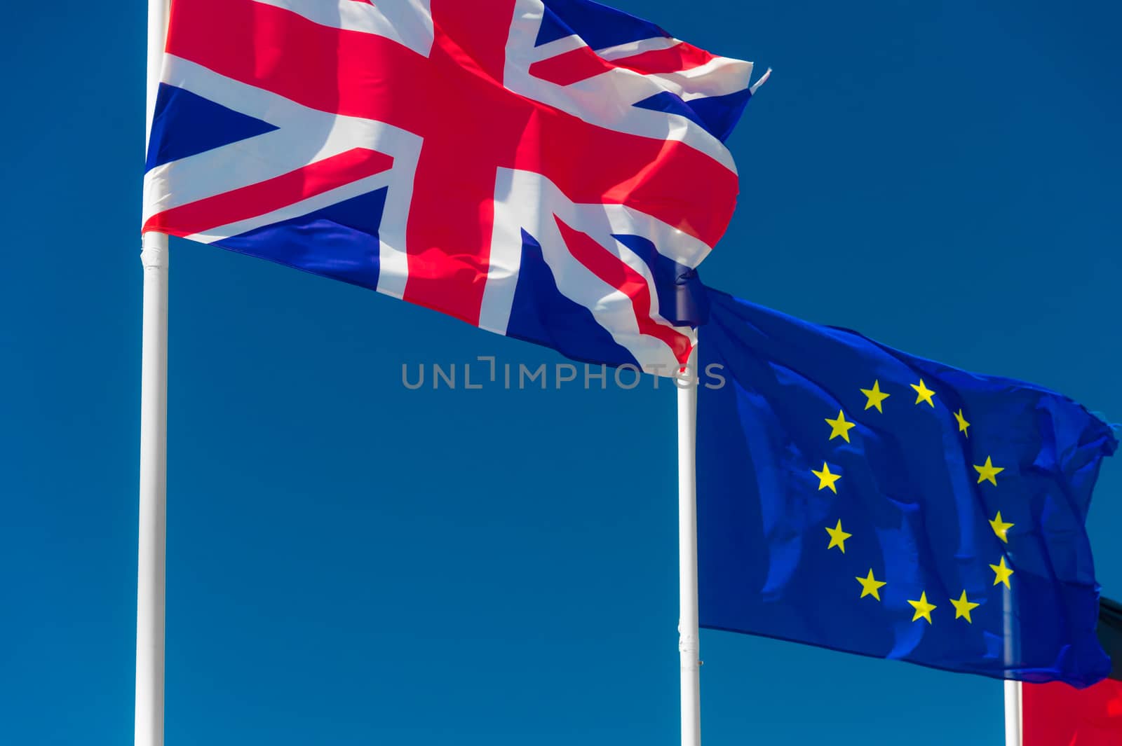 British flag and European flag waving against blue sky in Wimereux, France.