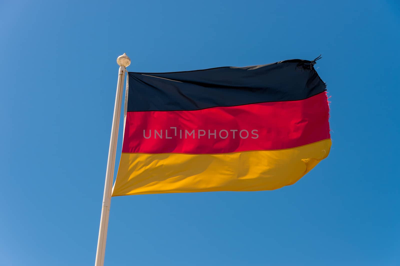German flag waving against blue sky in Wimereux, France.