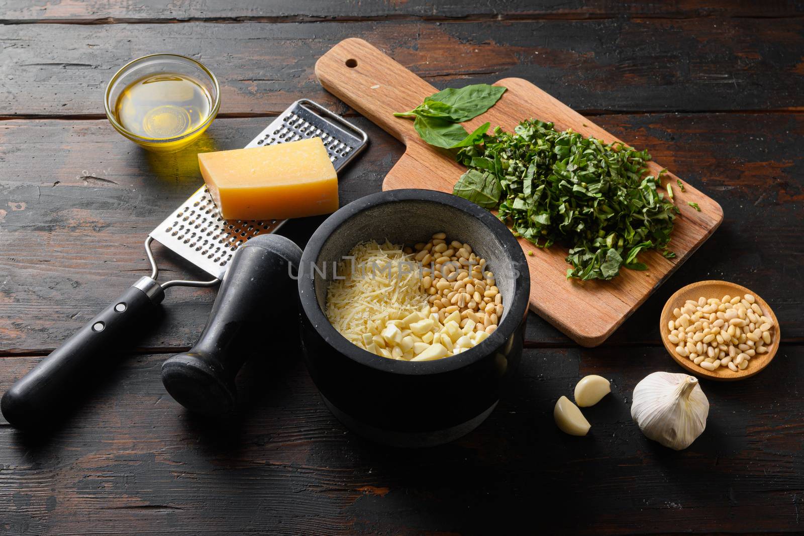 Pesto sauce cooking and mortar with ingredients . Basil, olive oil, parmesan, garlic, pine nuts. Top view on old vintage wooden table side view by Ilianesolenyi