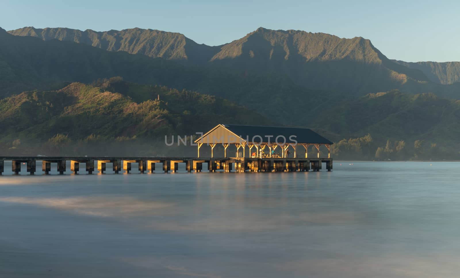 Sunrise lights the dawn sky above Hanalei Pier with the Na Pali coast in the background near Hanalei, Kauai, Hawaii