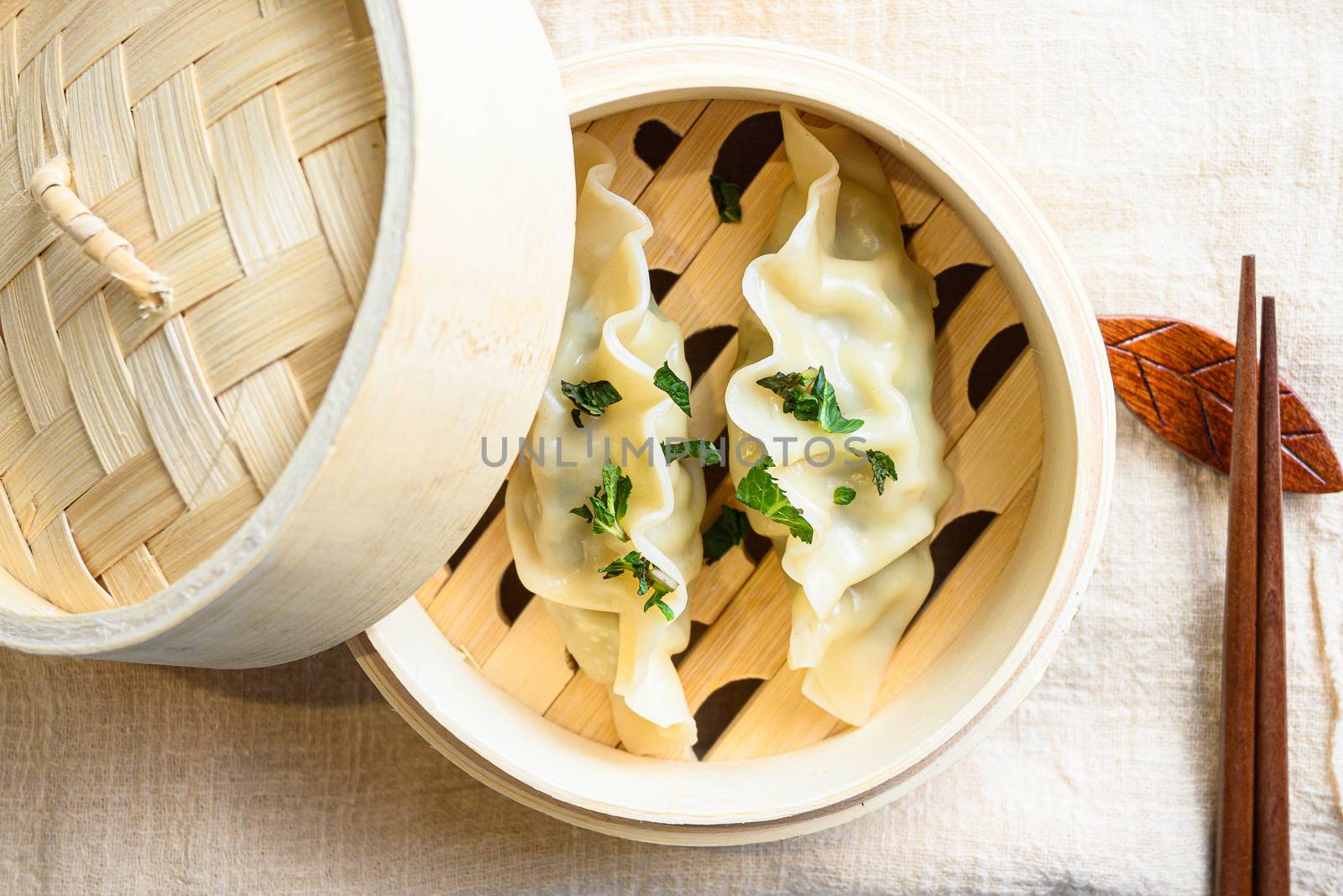Chinese snacks. chinese steamed dumpling. Chinese Traditional cuisine in wooden steamer, dumplings snack , on linen cloth served on white textured stone table top view close up.