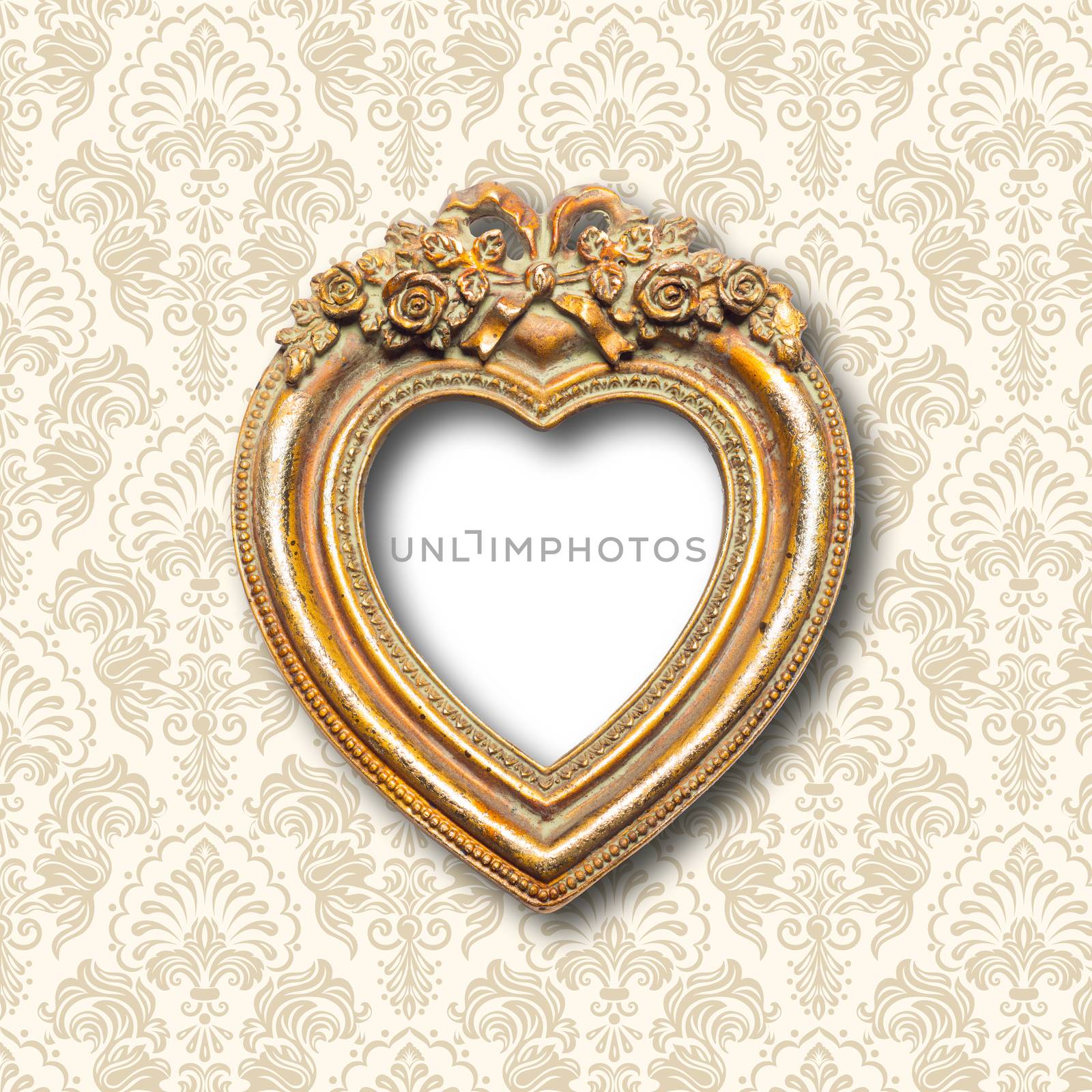 Old memories - old gold heart shape picture frame on pattern wall