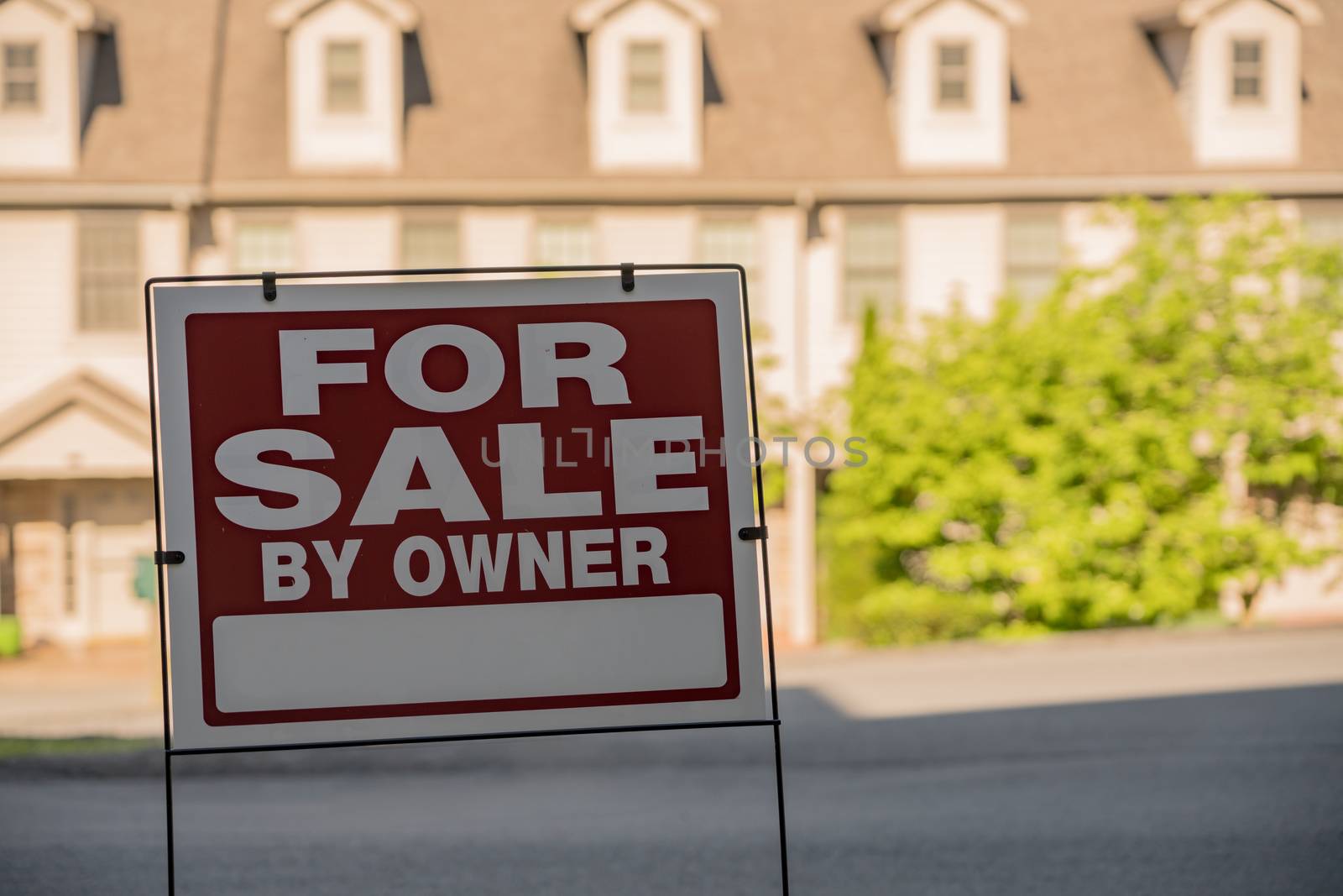 Blank for sale by owner sign in front of a row of town houses or homes in the USA