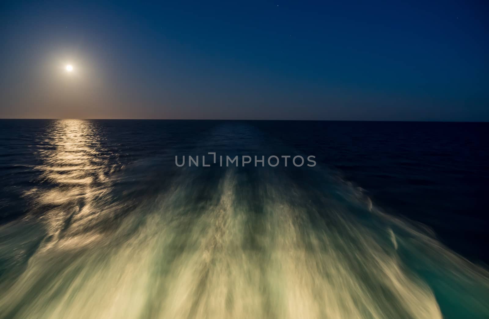 Moon rising over wake and waves of cruise ship at sea with concept of leaving or starting anew