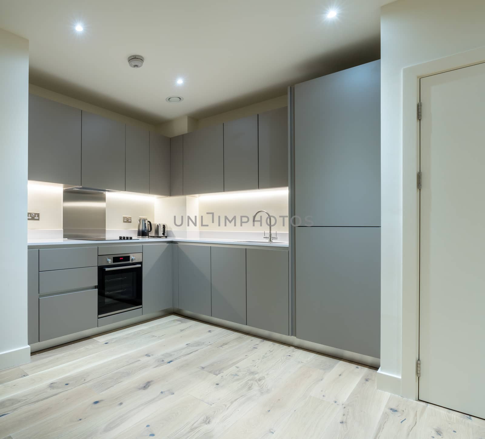 Clean new apartment kitchen in gray with modern appliances and equipment