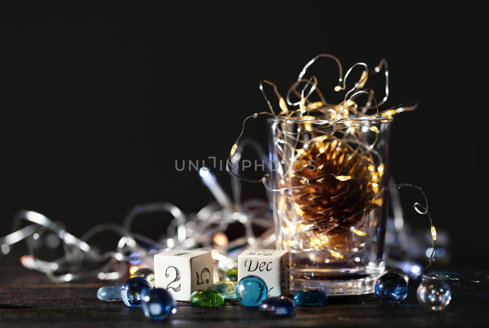 Beautiful Christmas background with  block calendar and glowing Christmas lights in a glass jar.
Calendar with the date of December 25.