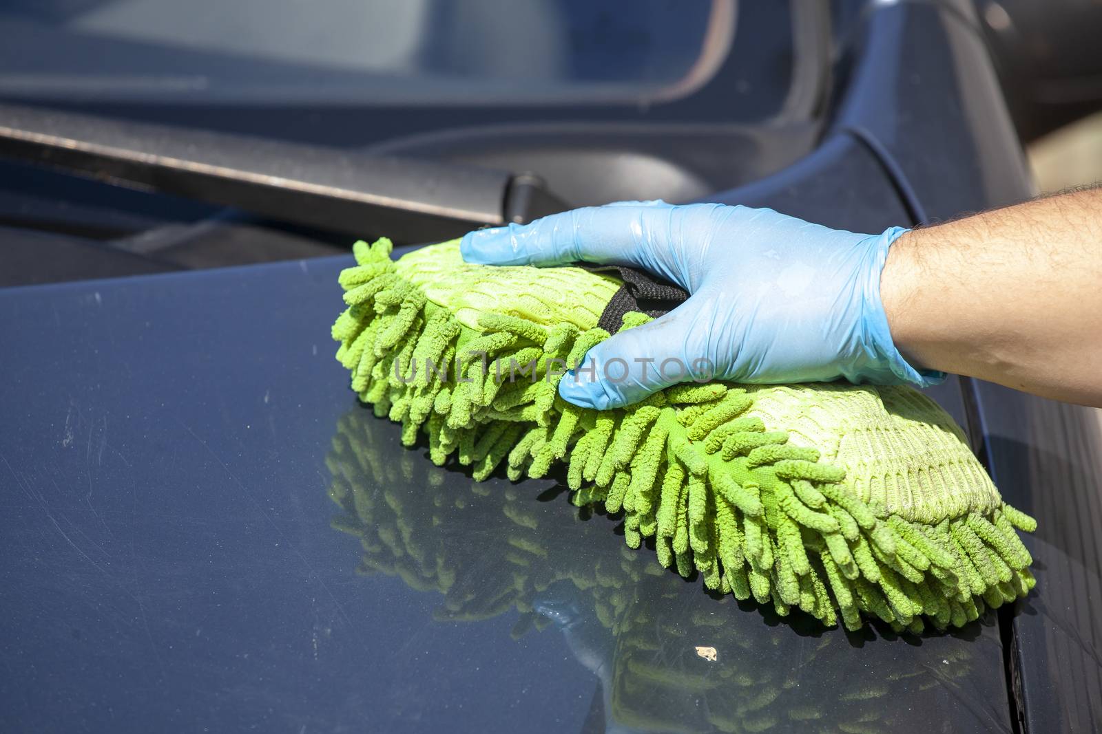 Woman clean blue car in glowes, green sponge in hand by adamr