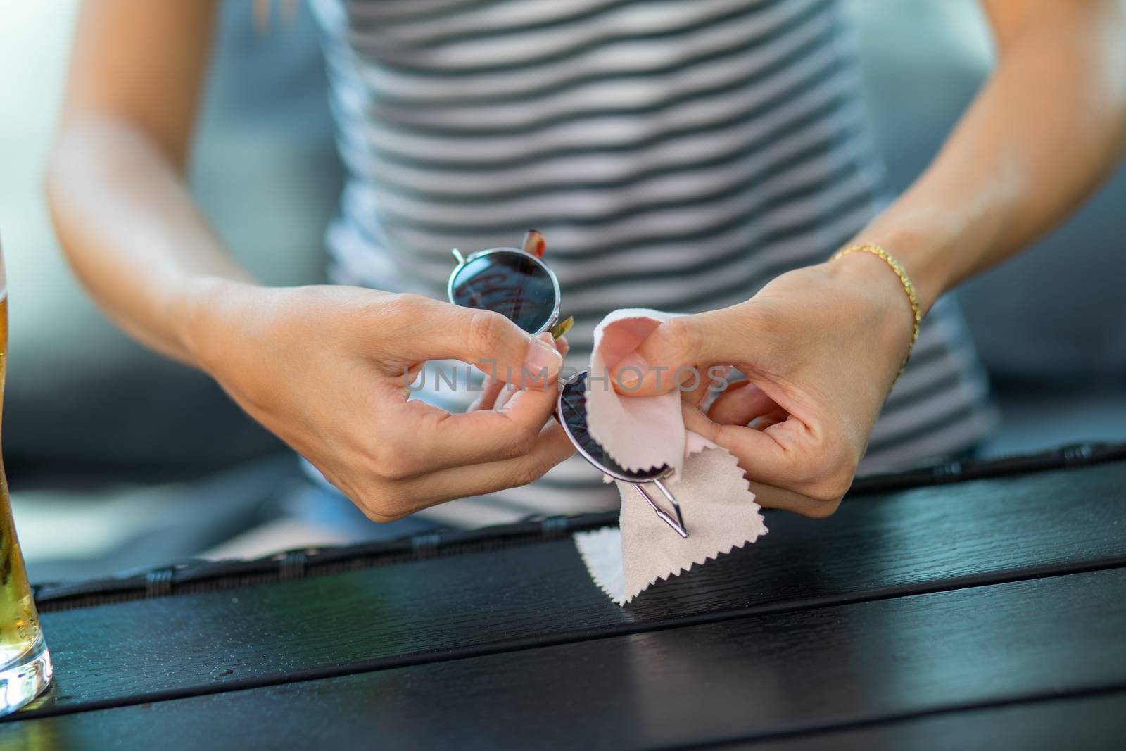 Wiping sunglasses - Woman hands cleaning her sun glasses with micro fiber cloth wipe, 