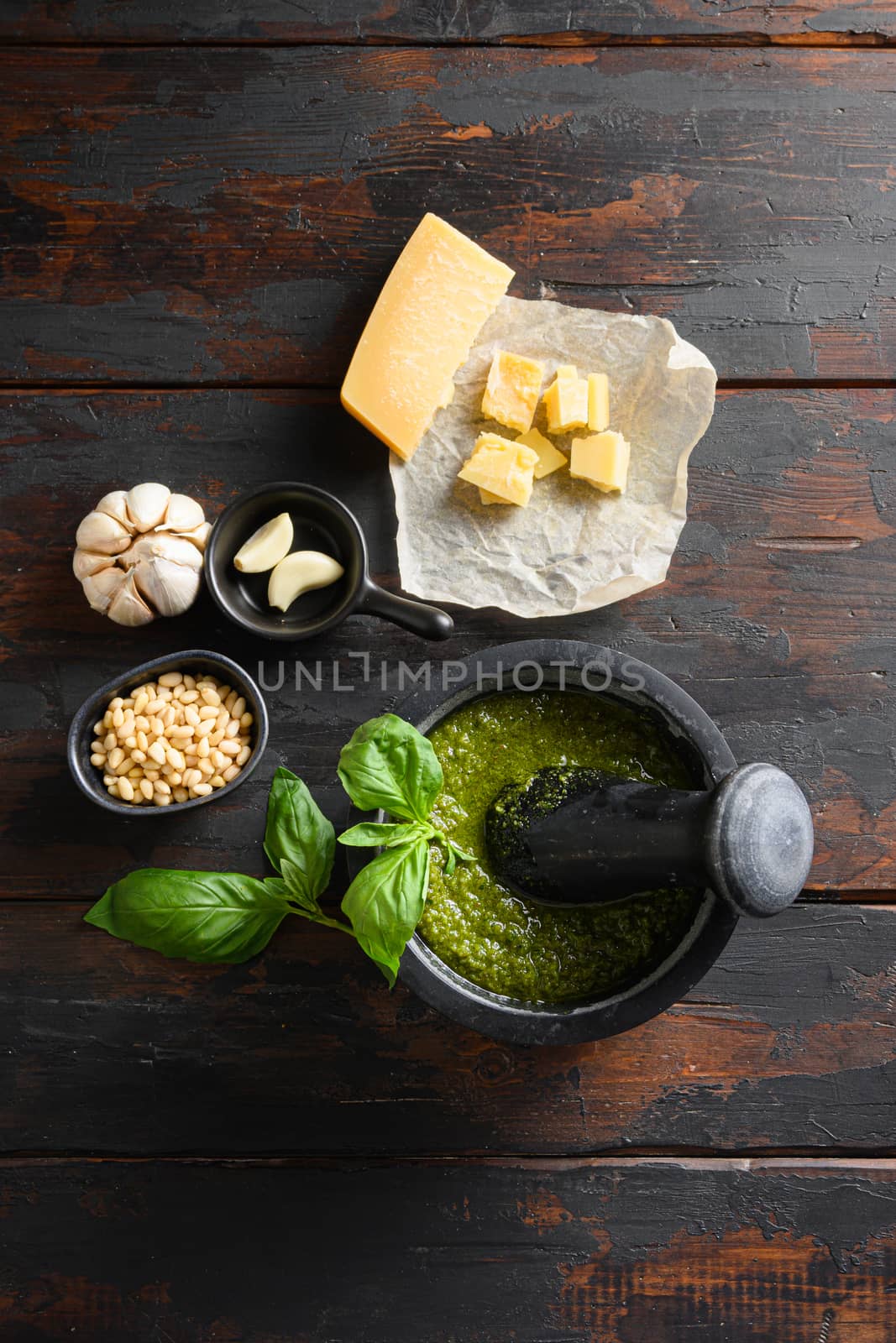 fresh Green basil pesto preparation in black mortar with italian recipe ingredients over old wood table copy space for text overhead by Ilianesolenyi