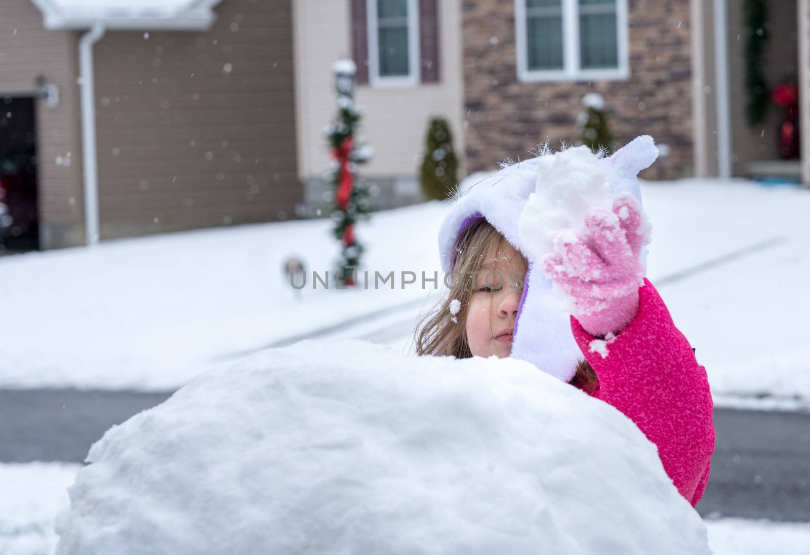 Toddler girl playing in the snow in front garden by steheap