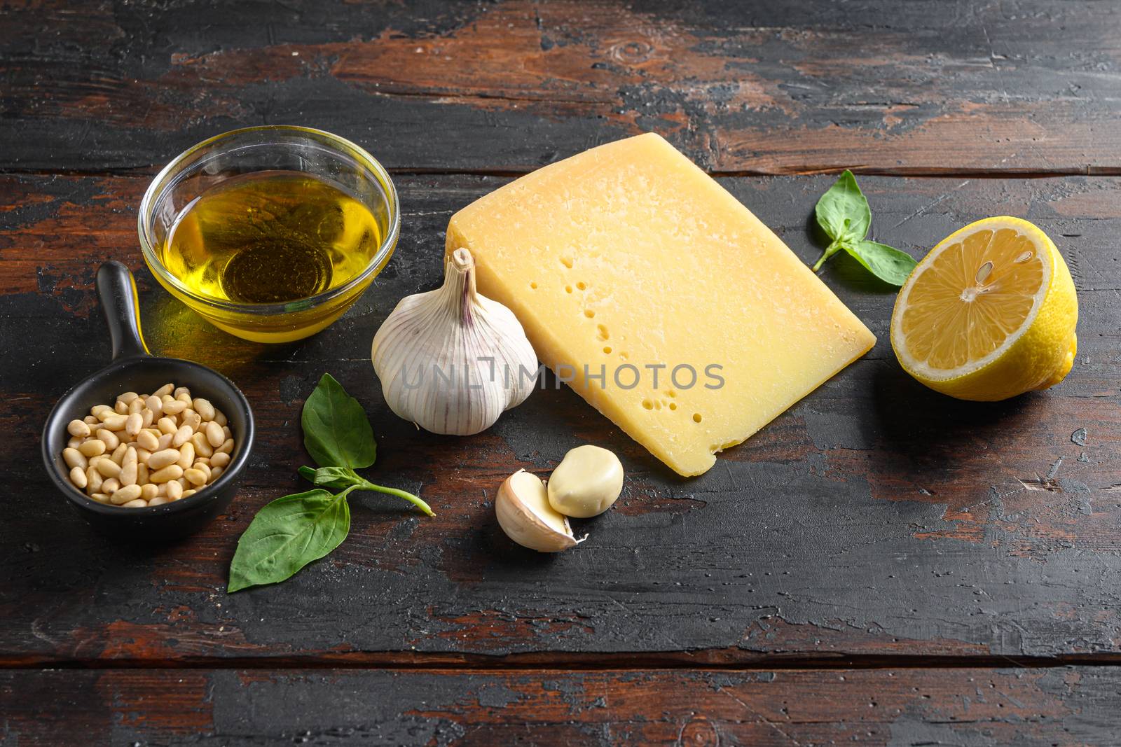Green basil pesto italian recipe Preparing Parmesan cheese, basil leaves, pine nuts, olive oil, garlic, salt and pepper. on wooden table side shot by Ilianesolenyi