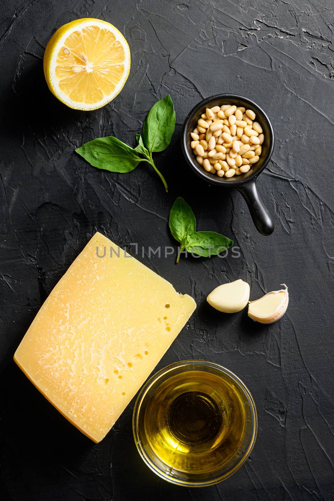 Pesto alla Genovese , Fresh ingredients for pesto genovese sauce on black stone background from above parmesan cheese, basil leaves, pine nuts, olive oil, garlic and salt. Traditional Italian cuisine. Top view. by Ilianesolenyi