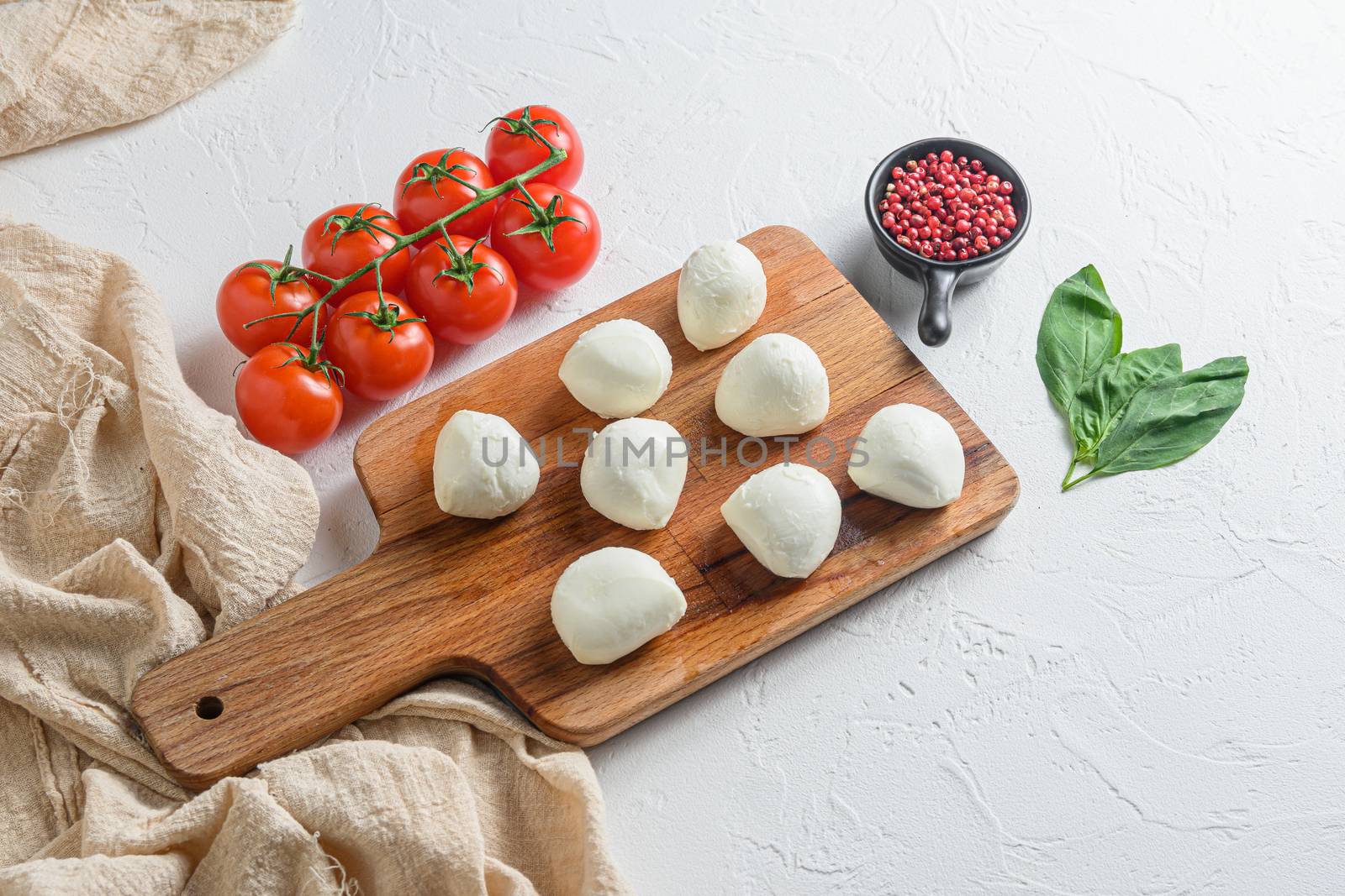 Mini balls of mozzarella cheese, on chop wood board ingredients for salad Caprese. over white background. Top view by Ilianesolenyi