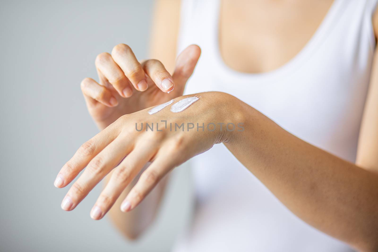 Young woman applying hand cream to care and protect skin, close up.