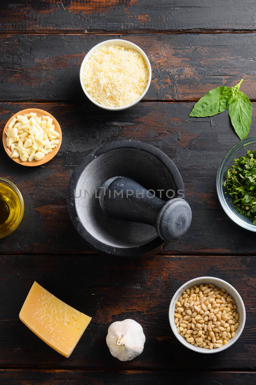 Mortar and Fresh ingredients for pesto genovese sauce Grated parmesan cheese, basil leaves, pine nuts, olive oil, garlic and salt on wood old table top view by Ilianesolenyi