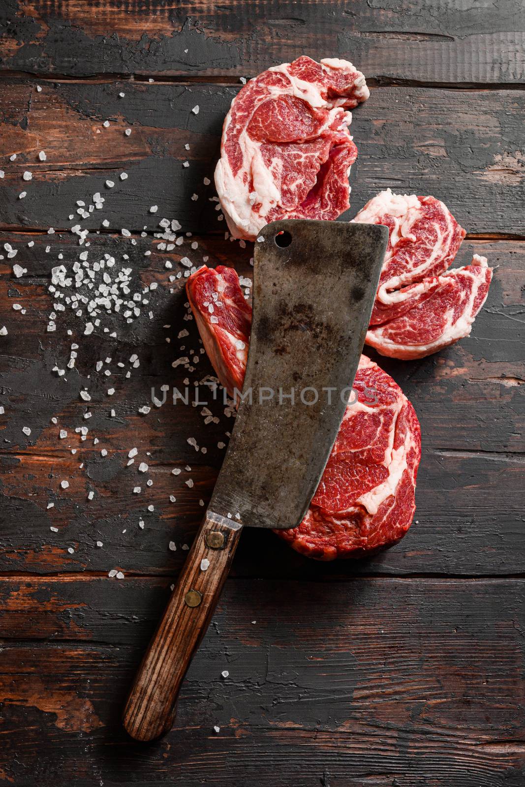raw cowboy steak and Chuck eye roll with seasonings on old butchery wood background, prime rib.