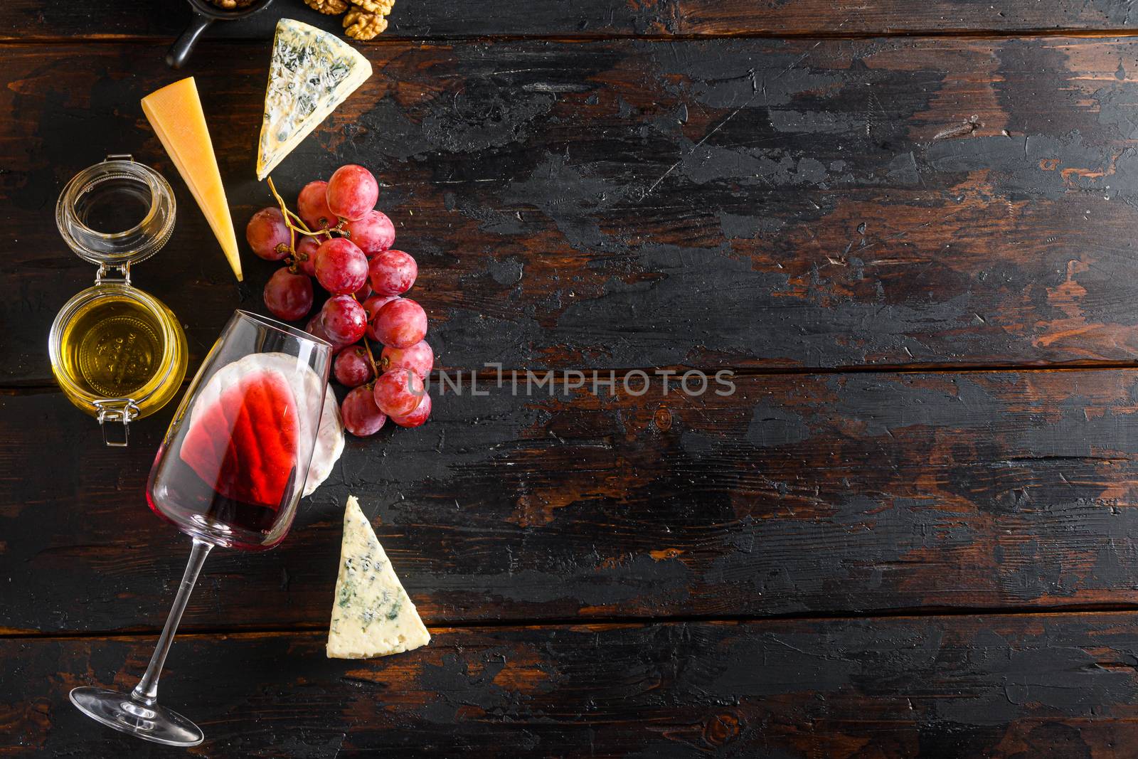 molded cheeses and snacks red wine glass honey grapes on old vintage dark wooden table Top view. Free space for text
