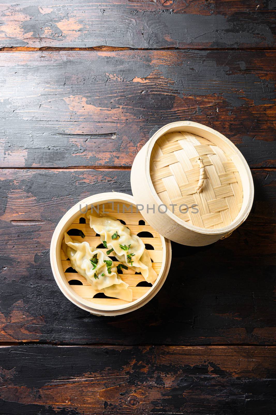 Dim sum dumplings in steamer over old rustic dark table top view space for text by Ilianesolenyi