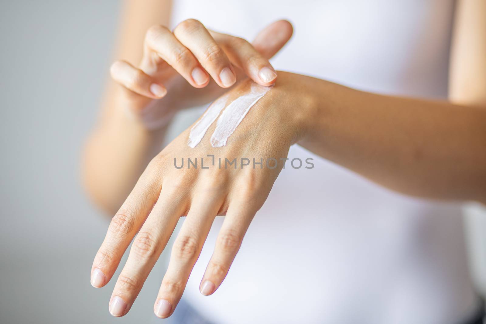 Young woman applying hand cream to care and protect skin, close up.