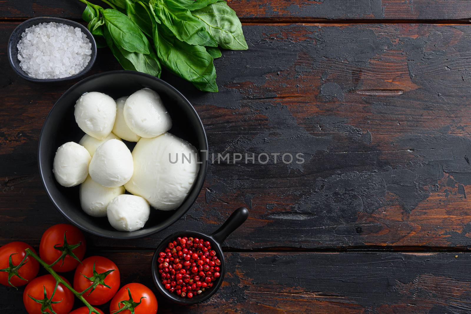 Raw ripe Mozzarella cheese balls with fresh basil leaves and cherry tomatoes, the ingredients , on old wood background top view space for text by Ilianesolenyi