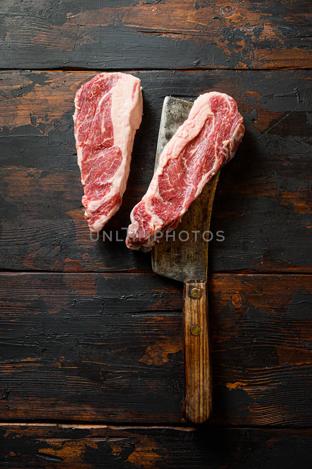 Raw Chuck Tenders marbled black angus premium beef on meat cleaver. Organic farm cowboy beef. Dark background. Top view. Copy space