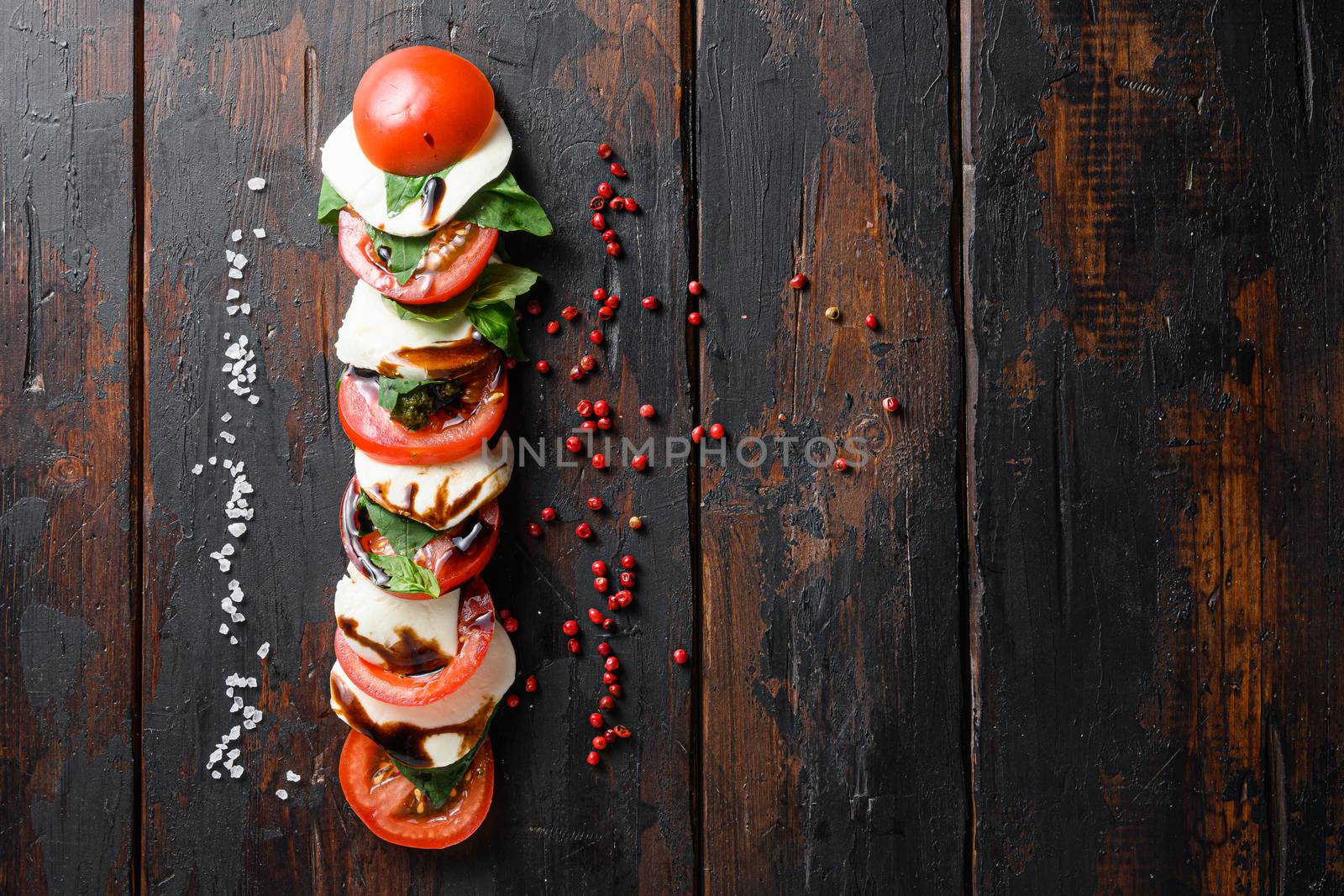 Concept Top view of fresh italian caprese salad with tomatoes, mozzarella, green basil sliced on old kitchen table top view space for text by Ilianesolenyi