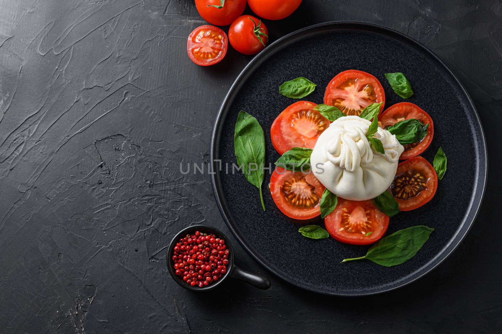 Burrata, Italian fresh cheese made from cream and milk of buffalo or cow. on black plate over black stone surface top view space for text. by Ilianesolenyi