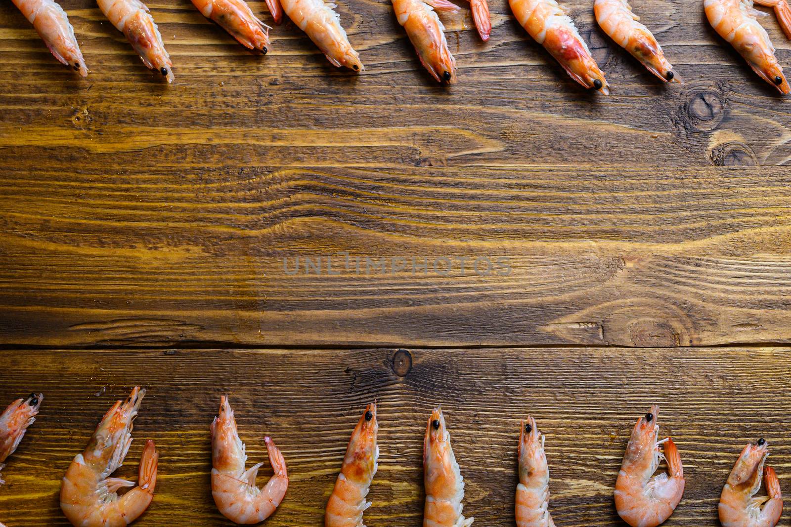 Concept of raw fresh shrimp prawns frame on wood background table with space for text by Ilianesolenyi