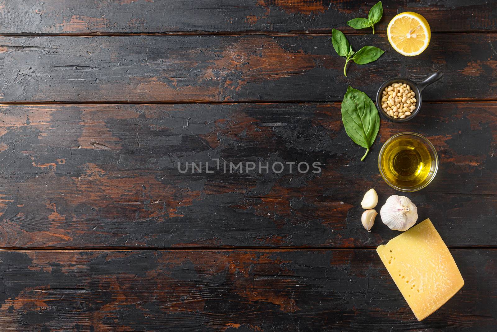 Different ingredients for pesto. . Parmesan cheese, basil leaves, pine nuts, olive oil, garlic and salt. Traditional Italian cuisine. On the wood planks background space for text by Ilianesolenyi