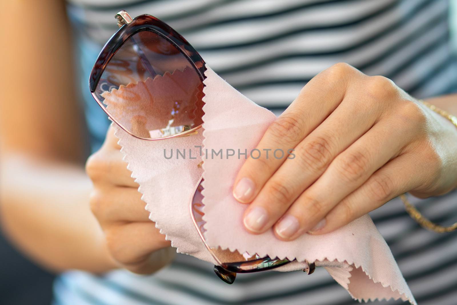 wiping sun glasses - Woman hands cleaning her sunglasses with micro fiber cloth wipe, wipping sunglasses