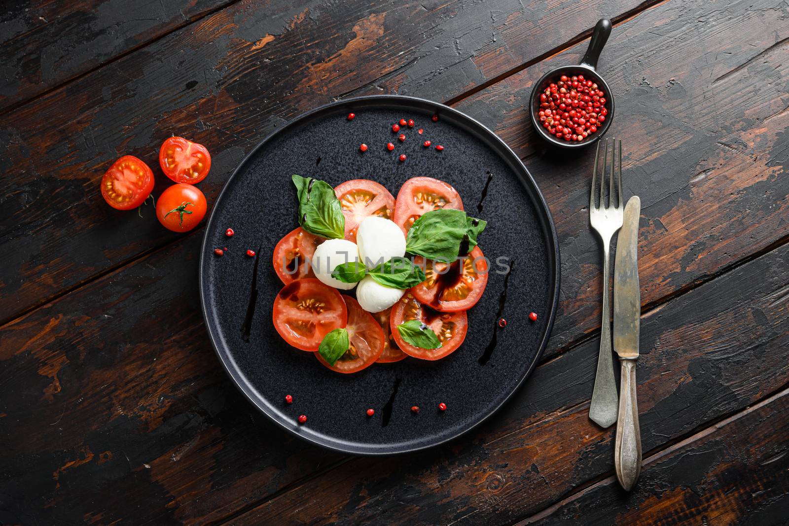 Tomato, basil, mozzarella Caprese salad with balsamic vinegar and olive oil. old wooden planks background over head top view.
