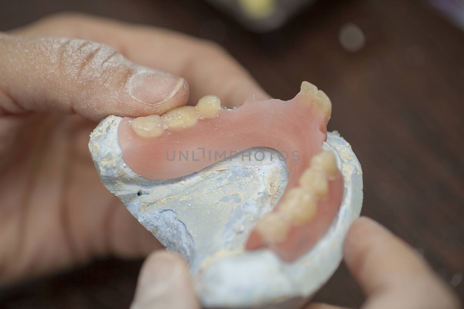 Dental technician check his work of denture prothesis in dental laboratory, close up