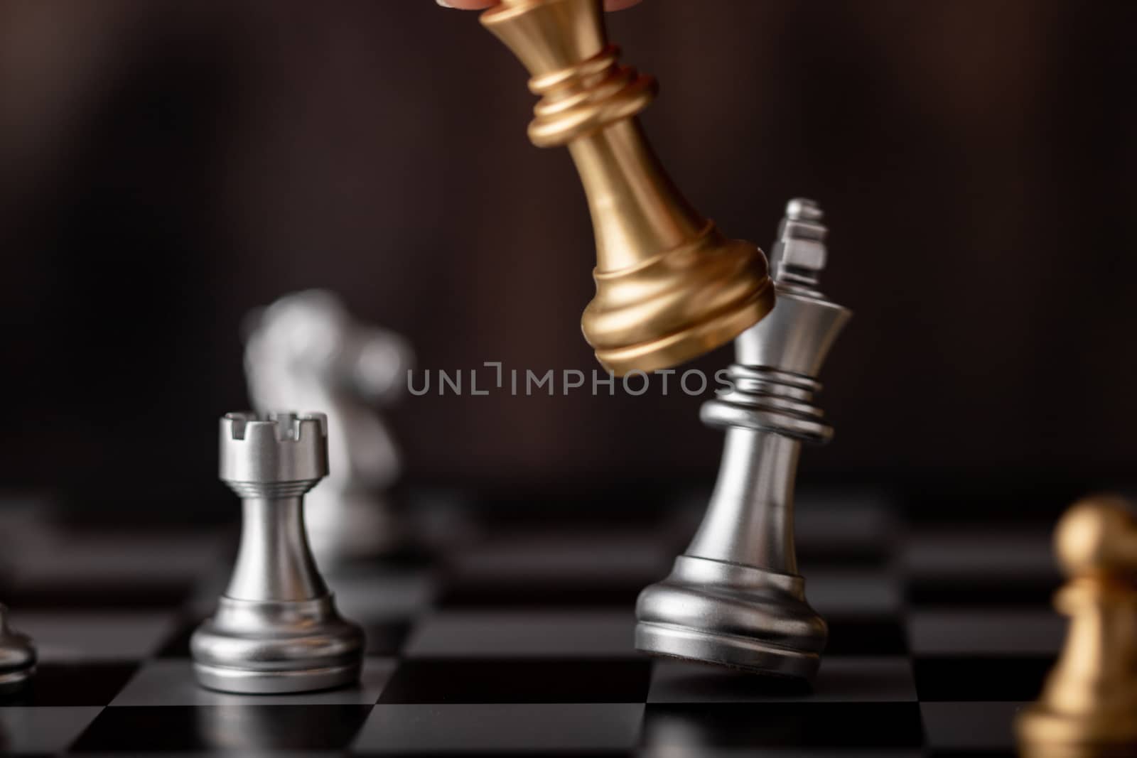 hand holding gold king attack silver leader in game on the chessboard