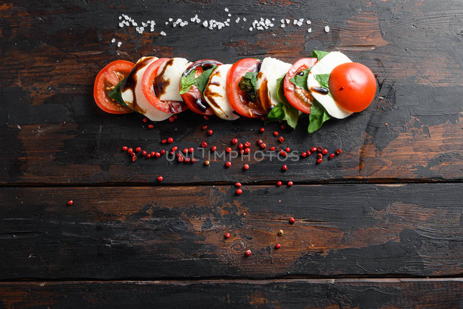 Top view of fresh italian caprese salad with tomatoes, mozzarella, green basil sliced on old kitchen table top view space for text.