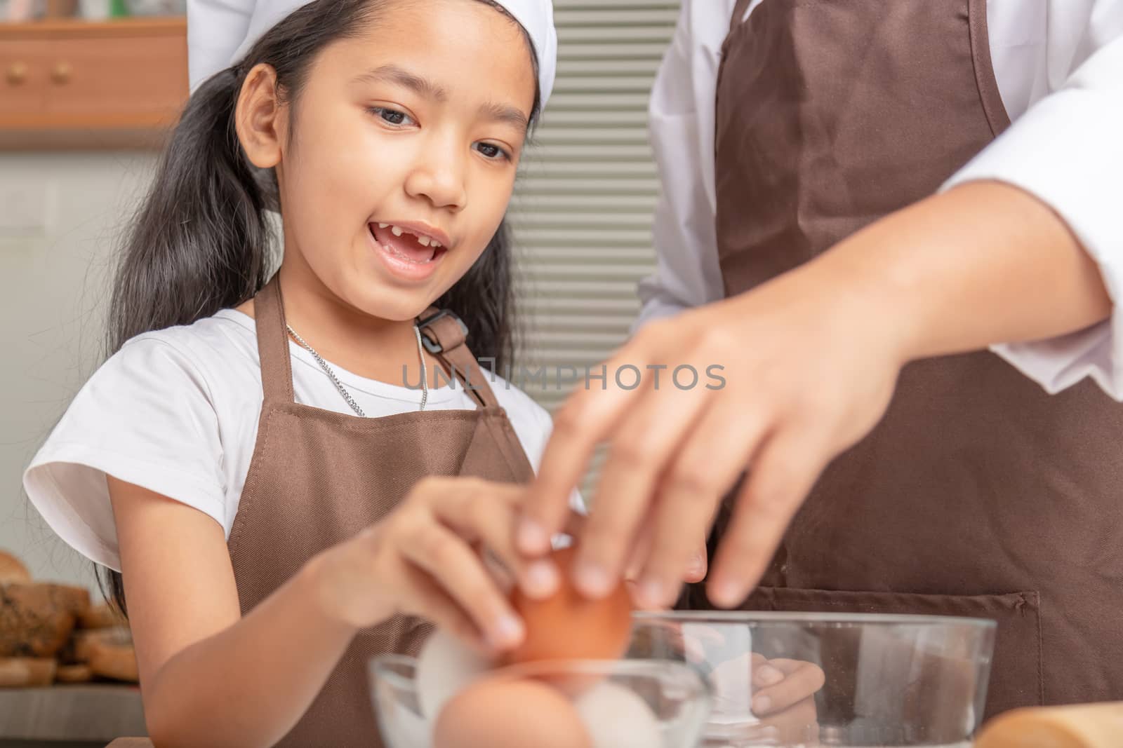 Mother and daughter are helping to collect eggs in clear cups placed on the table for cooking. Select focus shallow depth of field.