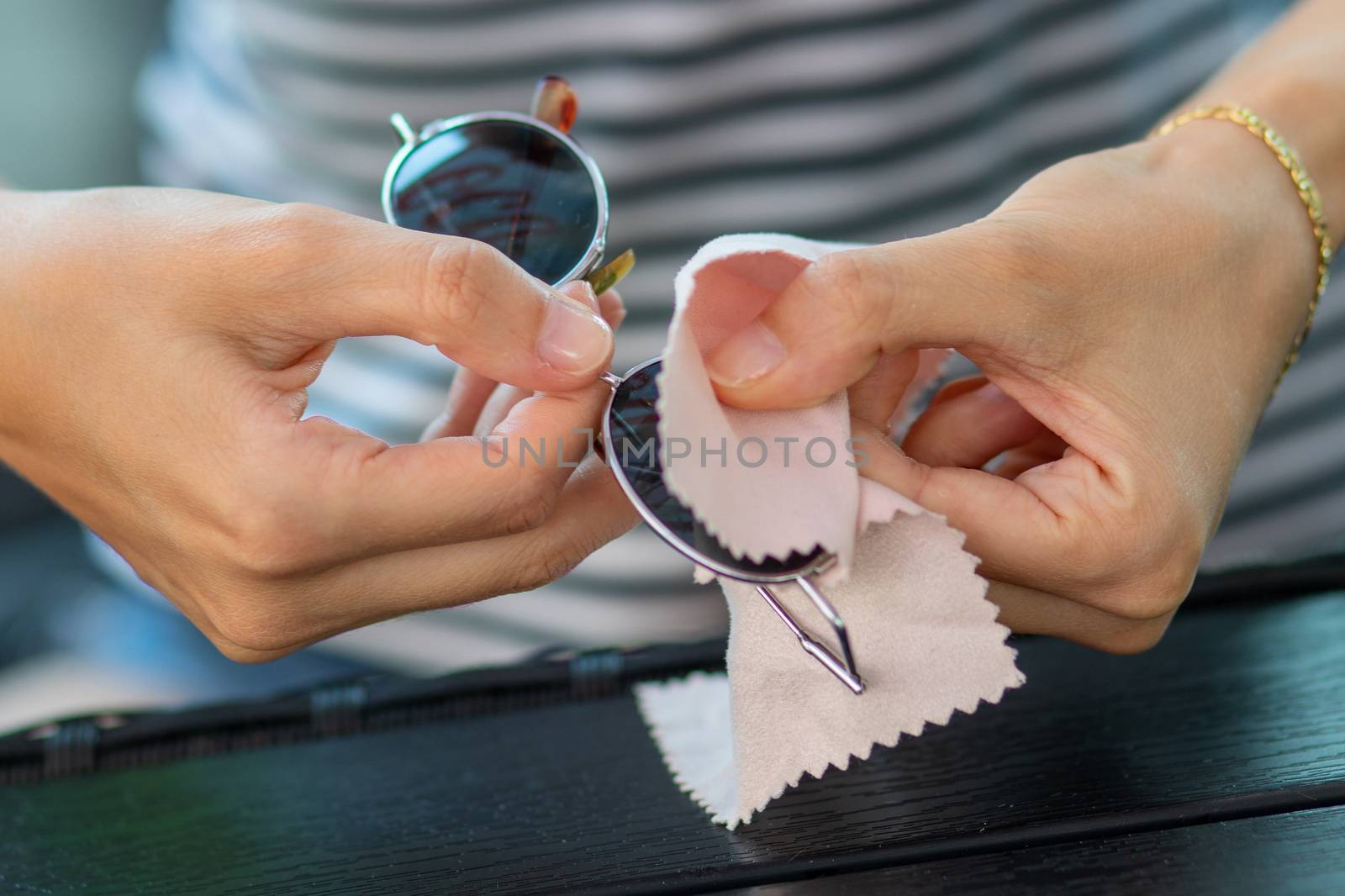 Wiping sunglasses - Woman hands cleaning her sun glasses with micro fiber cloth wipe, 