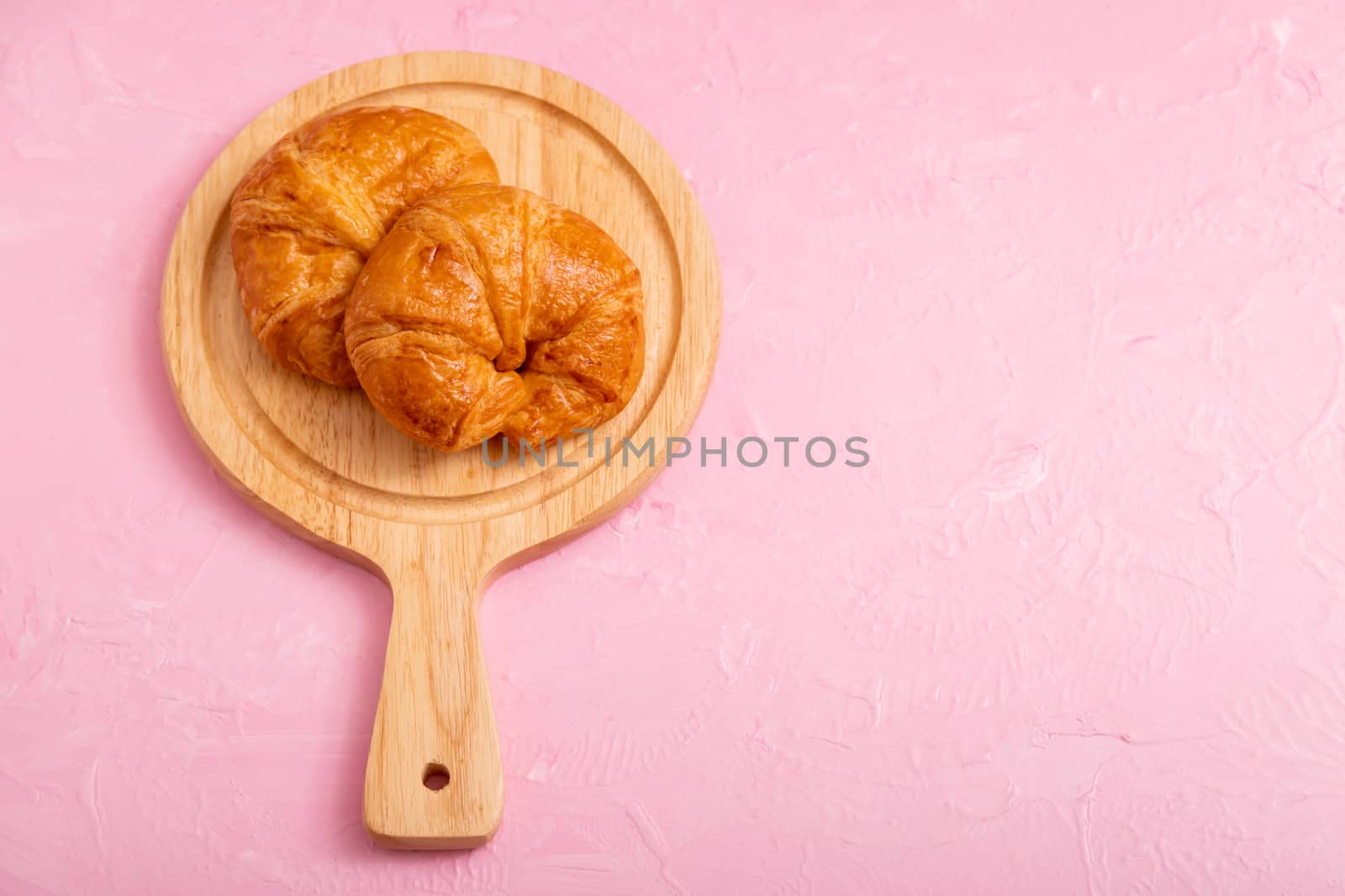 Top view croissants 2 pieces in the wooden board on the pink background and texture.