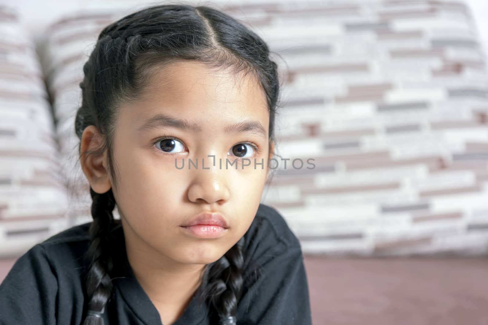 Close-up A little Asian girl in a black braid on the sofa