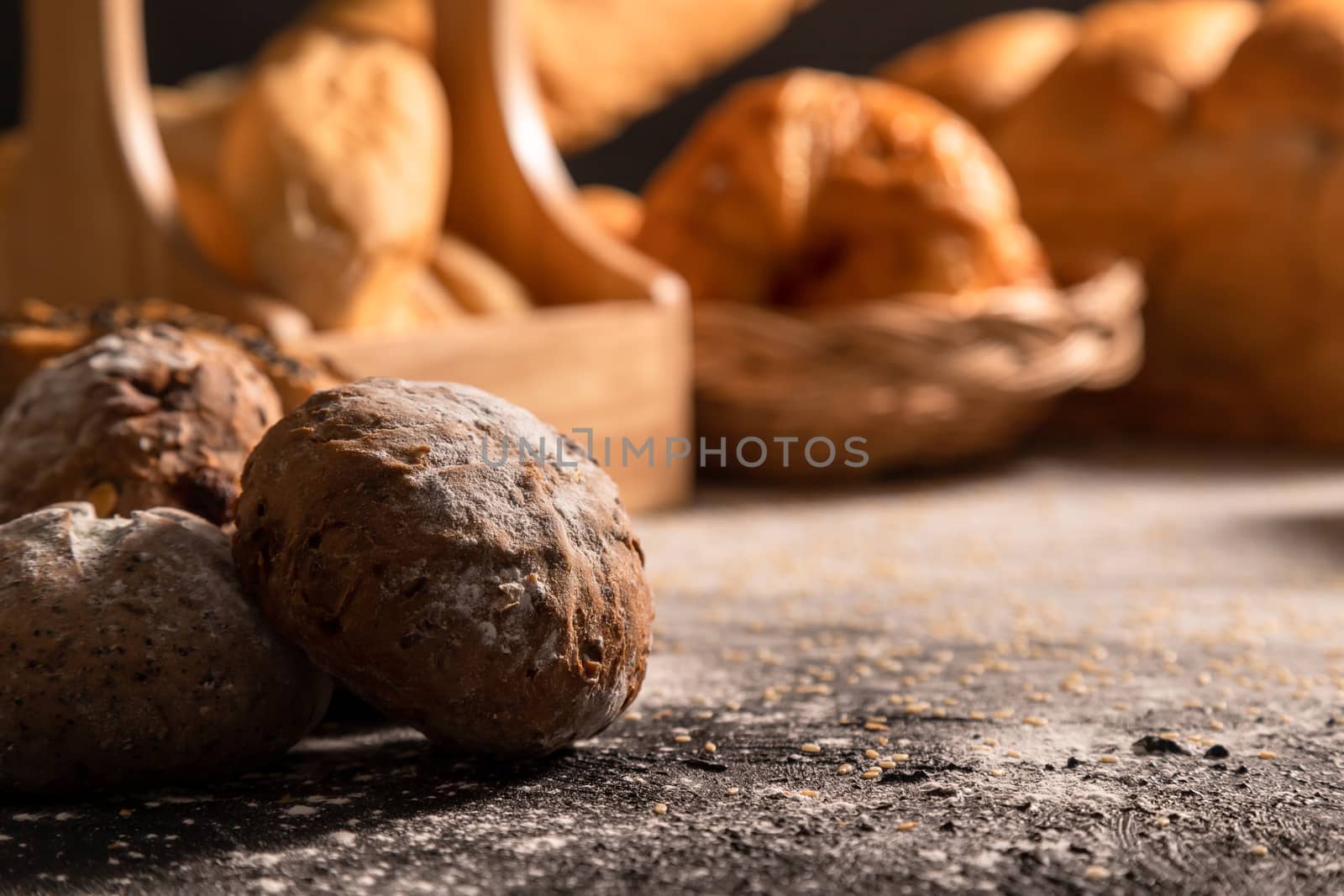 Close-up loaves of bread with sunlight in the morning on the wooden black table with sesame and variety of bakery.