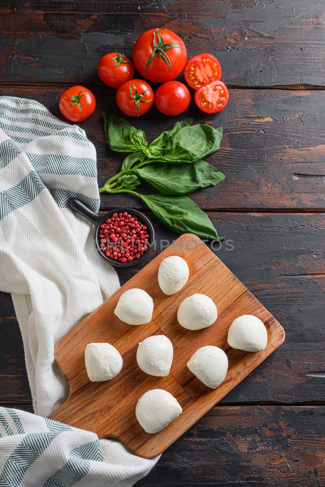 Mozzarella cheese, basil tomato cherry over old wood background table top view vertical.