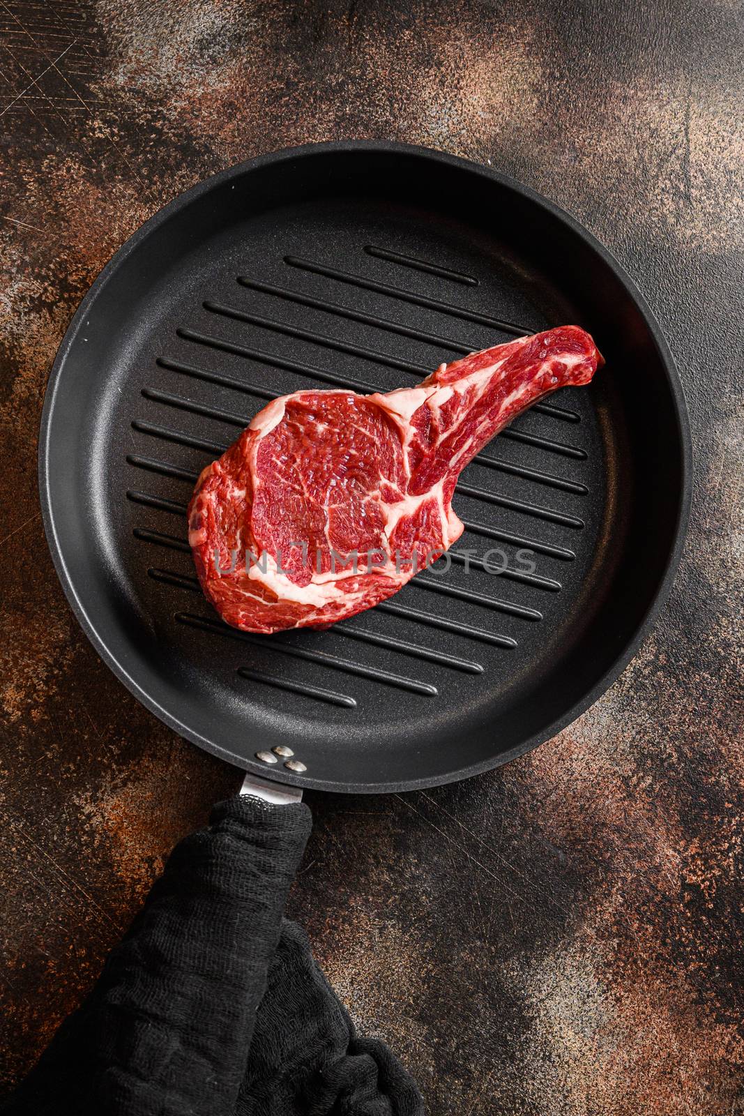 Bone In Steak on the grill pan skillet or Dallas steak raw top view. ove rustic metal dark background table.
