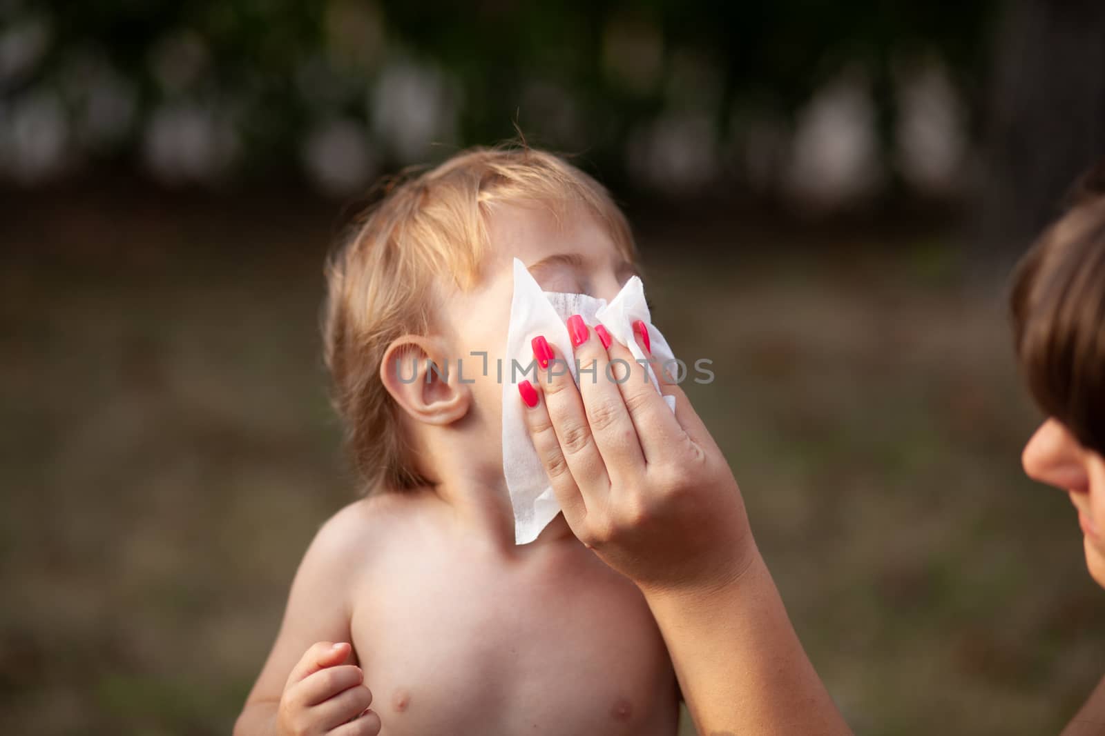 Hygiene - mom wiping the baby nose and face with wet wipes. Cleaning wipe, pure, clean, outdoor