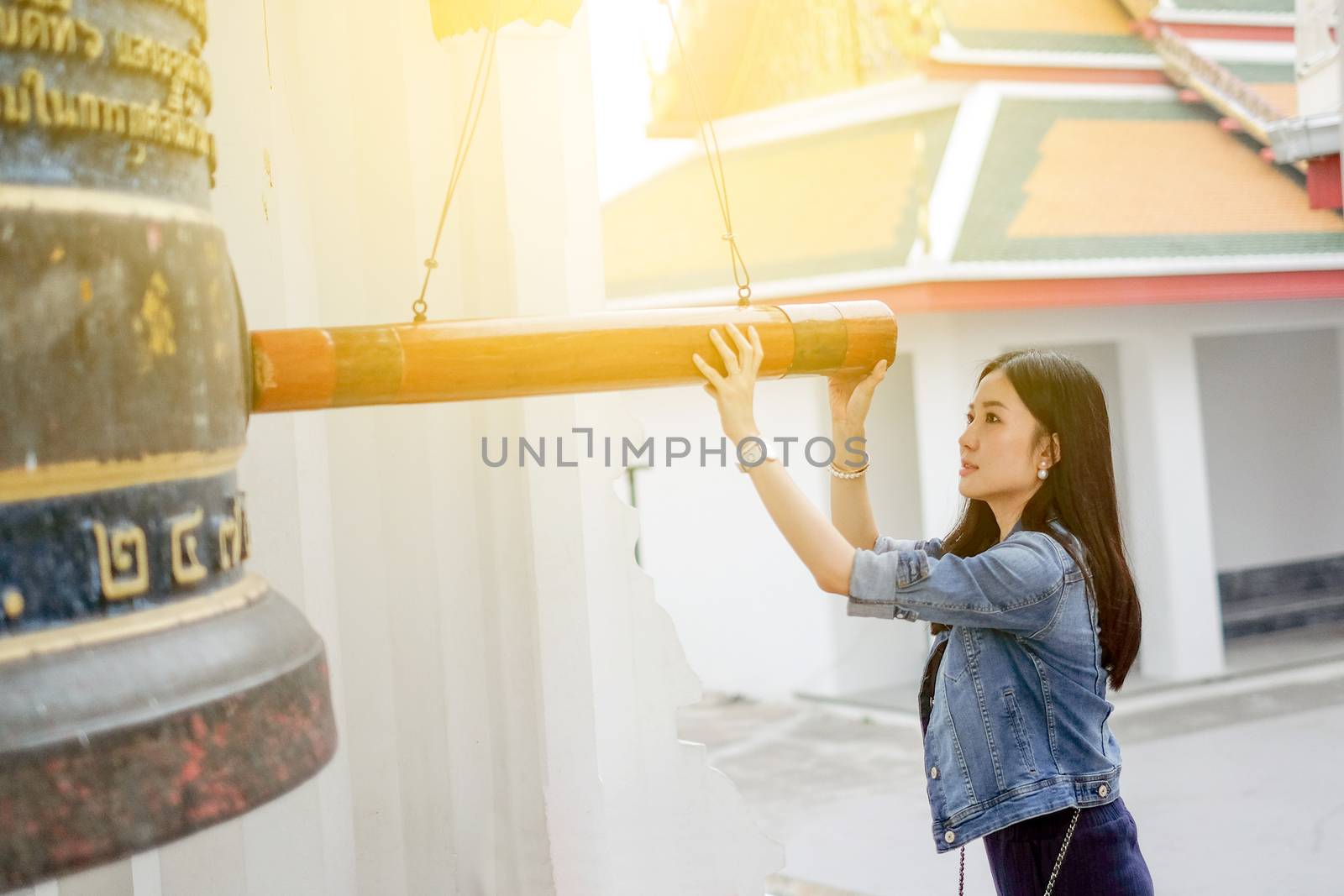 Woman ringing a bell in a Buddhist temple in Thailand